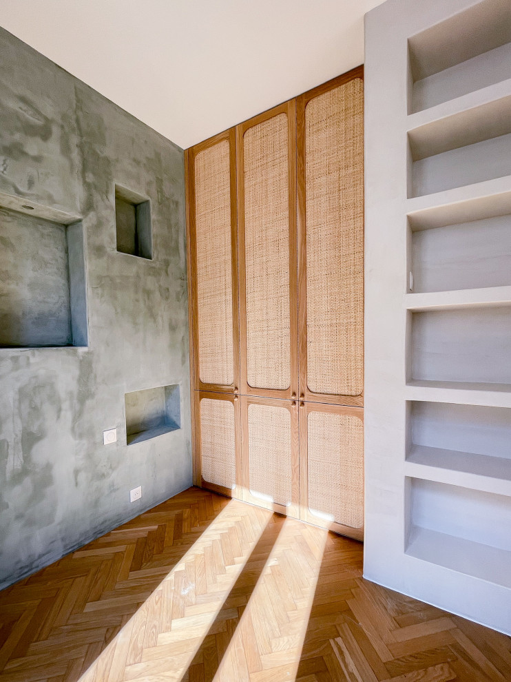 Photo of a mid-sized transitional gender-neutral built-in wardrobe in Paris with flat-panel cabinets, light wood cabinets, light hardwood floors and brown floor.