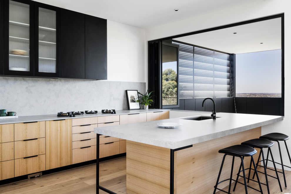Mid-sized trendy single-wall light wood floor kitchen pantry photo in Melbourne with an island, a single-bowl sink, flat-panel cabinets, light wood cabinets, quartz countertops, gray backsplash, stone slab backsplash, black appliances and gray countertops