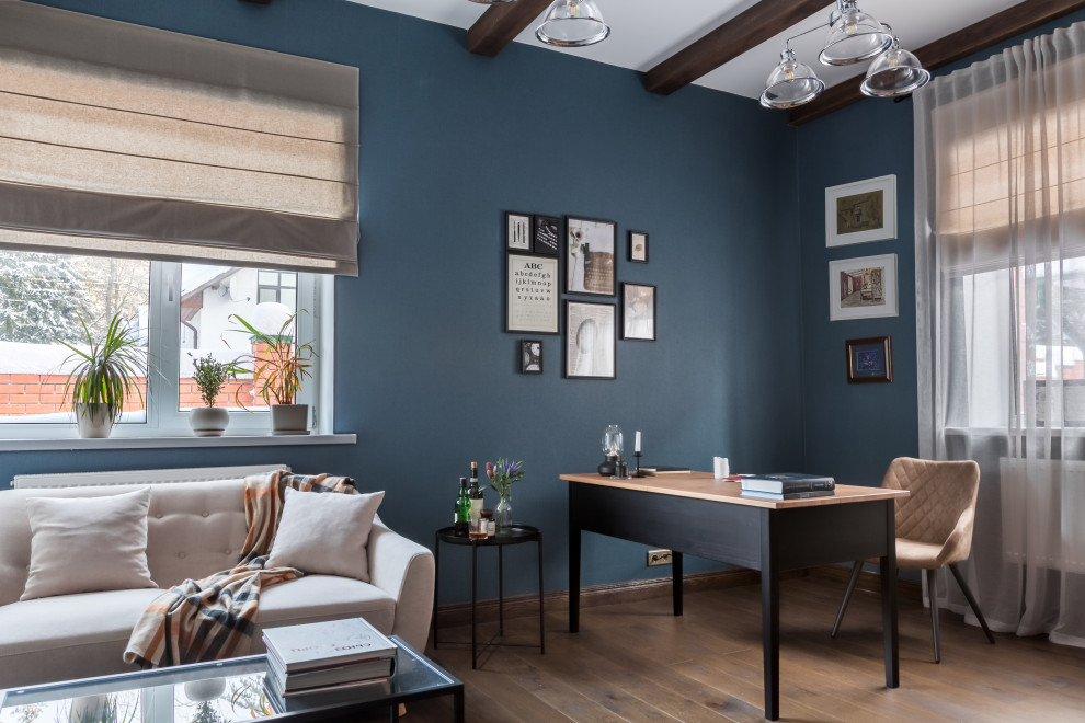 Mittelgroßes Landhausstil Lesezimmer mit blauer Wandfarbe, dunklem Holzboden, freistehendem Schreibtisch, braunem Boden, freigelegten Dachbalken und Tapetenwänden in Moskau