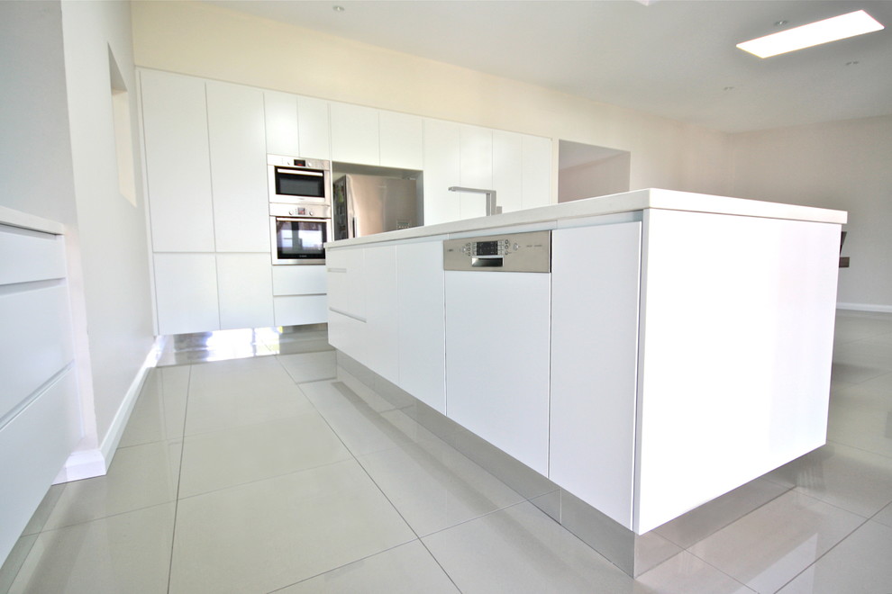 Design ideas for a large modern l-shaped eat-in kitchen in Sydney with an undermount sink, flat-panel cabinets, white cabinets, quartz benchtops, blue splashback, glass sheet splashback, stainless steel appliances, porcelain floors and multiple islands.