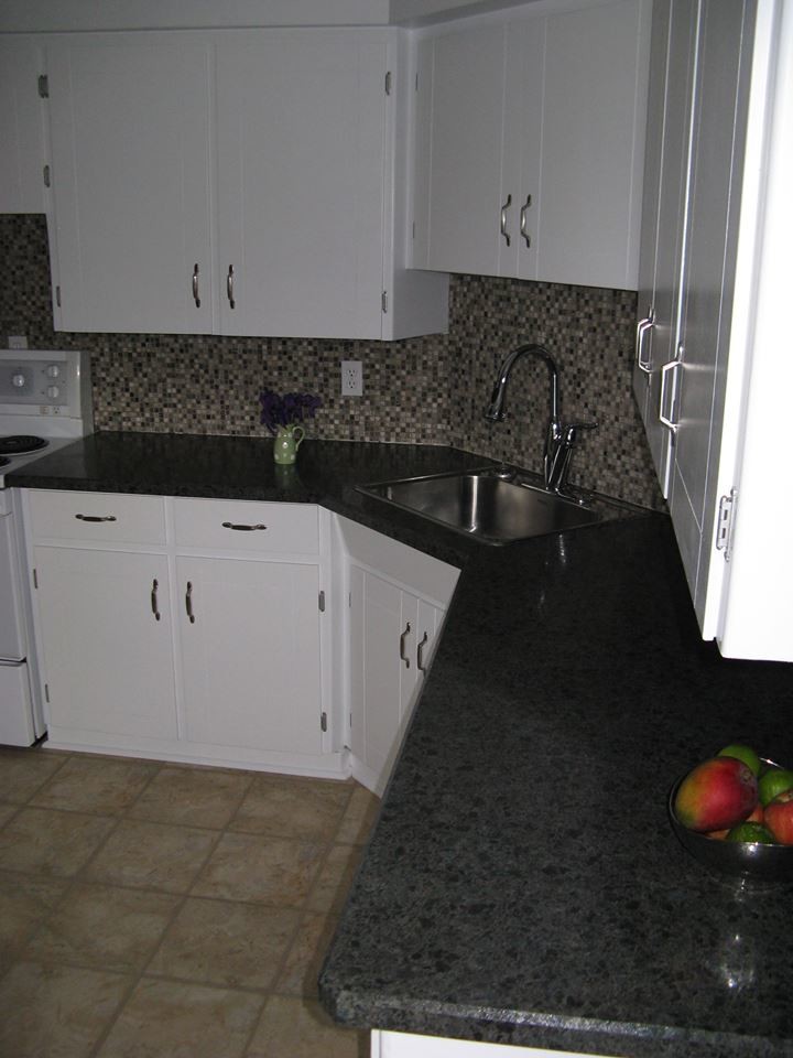 Transitional brown floor kitchen photo in Orange County with a drop-in sink, flat-panel cabinets, white cabinets, granite countertops, multicolored backsplash, mosaic tile backsplash and stainless steel appliances