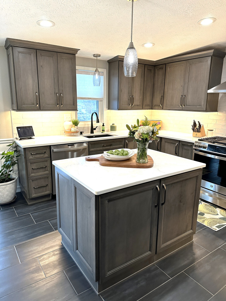 This is an example of a large transitional u-shaped eat-in kitchen in Detroit with an undermount sink, shaker cabinets, dark wood cabinets, quartz benchtops, white splashback, ceramic splashback, stainless steel appliances, porcelain floors, with island, grey floor and white benchtop.