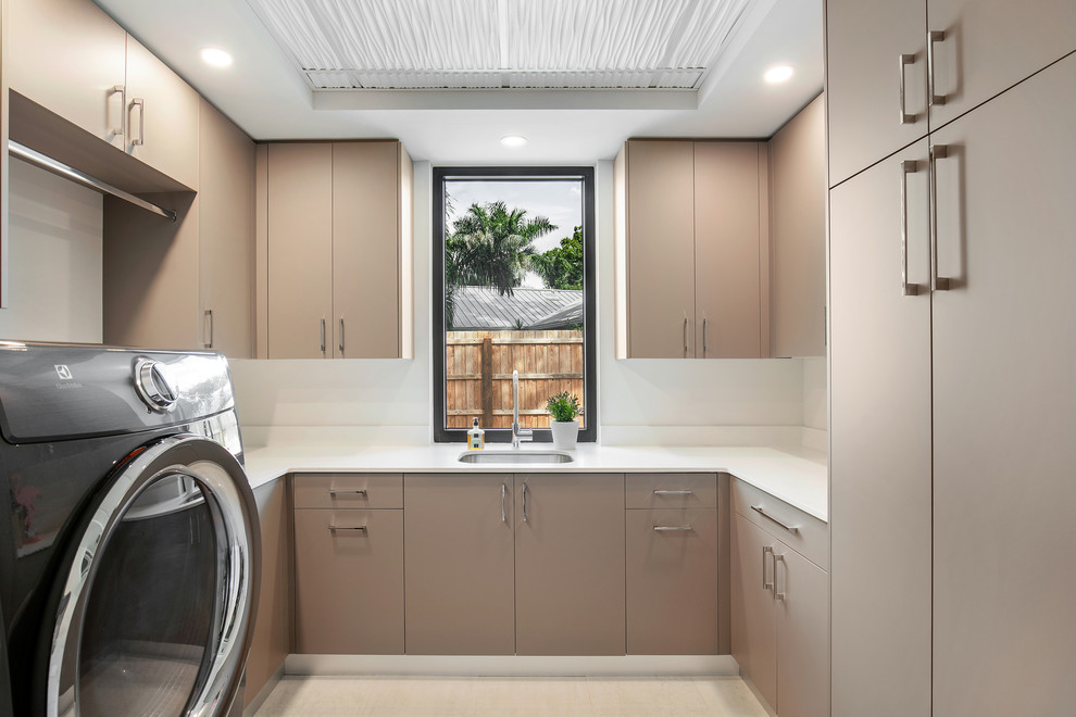 This is an example of a mid-sized modern u-shaped dedicated laundry room in Tampa with an undermount sink, flat-panel cabinets, beige cabinets, quartz benchtops, white walls, porcelain floors, a side-by-side washer and dryer, white floor and white benchtop.