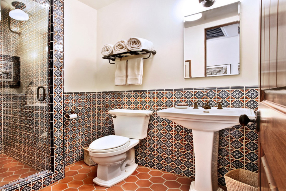 Kleines Mediterranes Duschbad mit Duschnische, Toilette mit Aufsatzspülkasten, farbigen Fliesen, weißer Wandfarbe, Waschtischkonsole, orangem Boden und Einzelwaschbecken in Los Angeles
