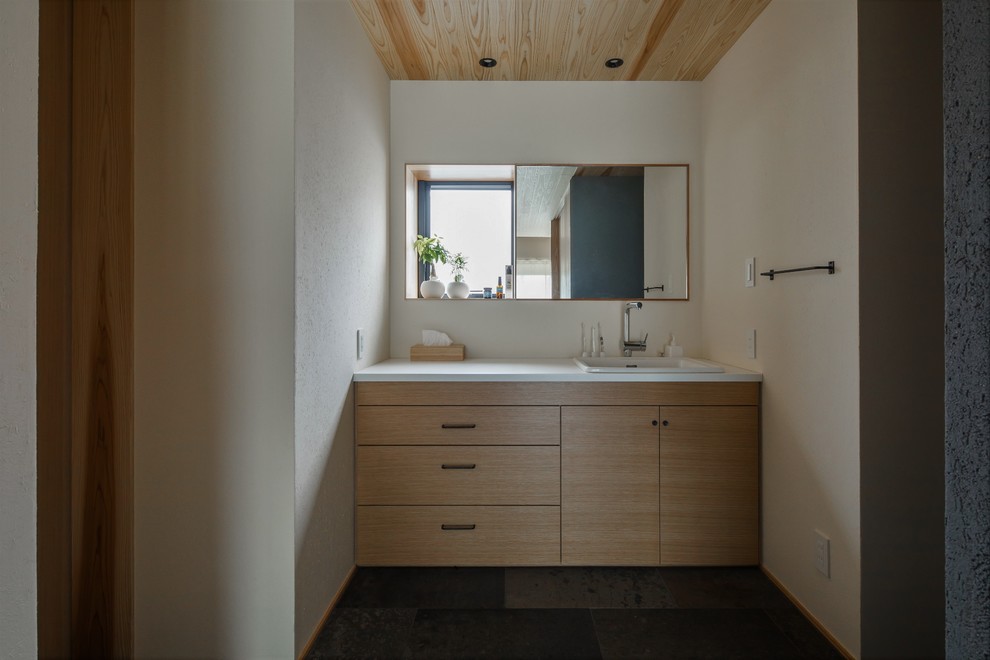 This is an example of a mid-sized asian powder room in Other with beaded inset cabinets, beige cabinets, white tile, beige walls, medium hardwood floors, a vessel sink, solid surface benchtops, beige floor and white benchtops.