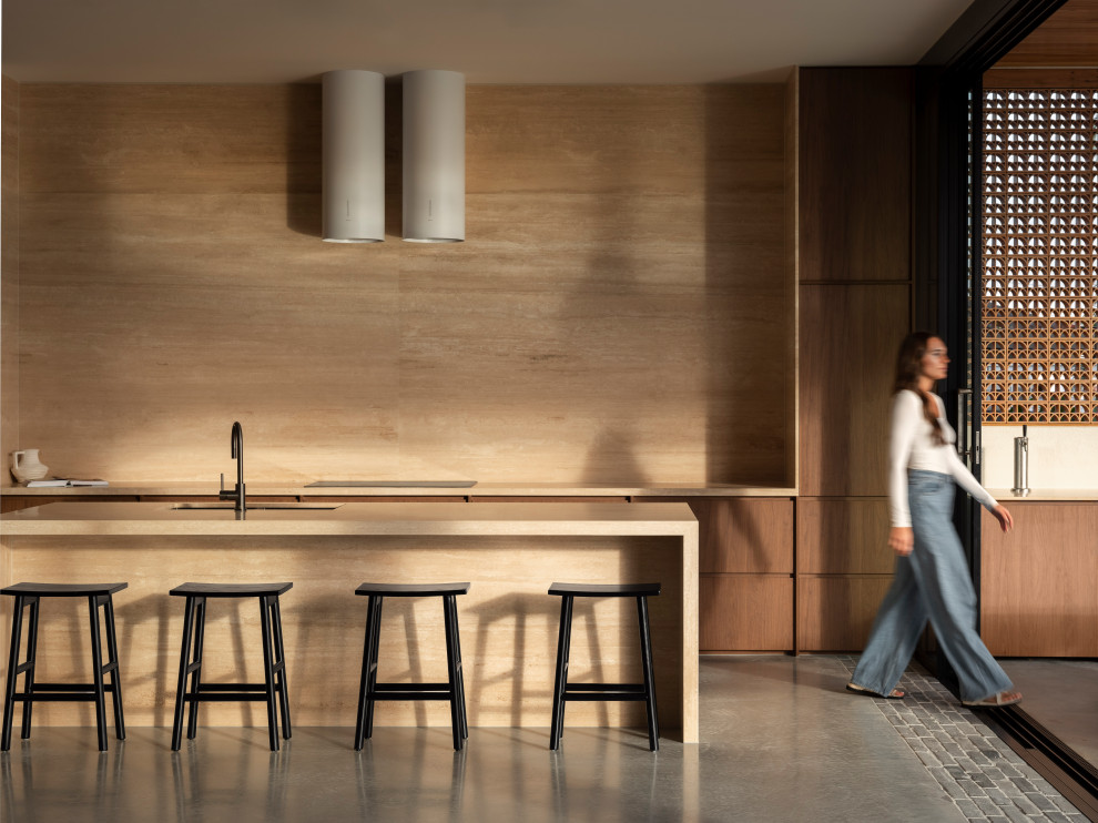 Inspiration for an expansive modern galley kitchen pantry in Gold Coast - Tweed with an undermount sink, flat-panel cabinets, dark wood cabinets, beige splashback, travertine splashback, concrete floors, with island, grey floor and beige benchtop.