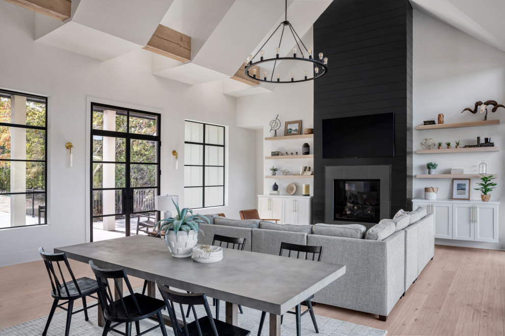 Inspiration for a medium sized rural kitchen/dining room in Austin with white walls, light hardwood flooring, a standard fireplace, a timber clad chimney breast, brown floors, exposed beams and tongue and groove walls.
