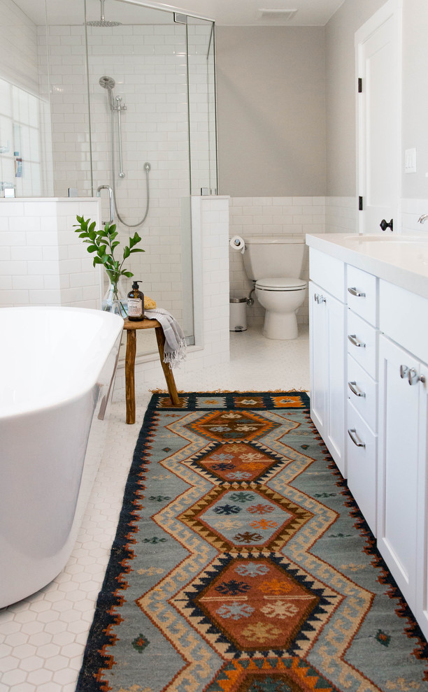Inspiration for a mid-sized transitional master bathroom in Las Vegas with recessed-panel cabinets, white cabinets, a freestanding tub, a corner shower, a two-piece toilet, white tile, subway tile, grey walls, ceramic floors and a hinged shower door.
