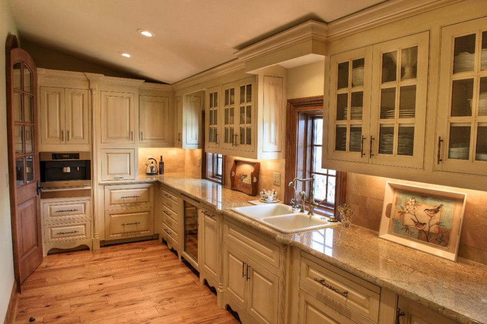 Mid-sized transitional l-shaped medium tone wood floor and beige floor enclosed kitchen photo in Toronto with a double-bowl sink, glass-front cabinets, beige cabinets, granite countertops, beige backsplash, ceramic backsplash, stainless steel appliances and no island