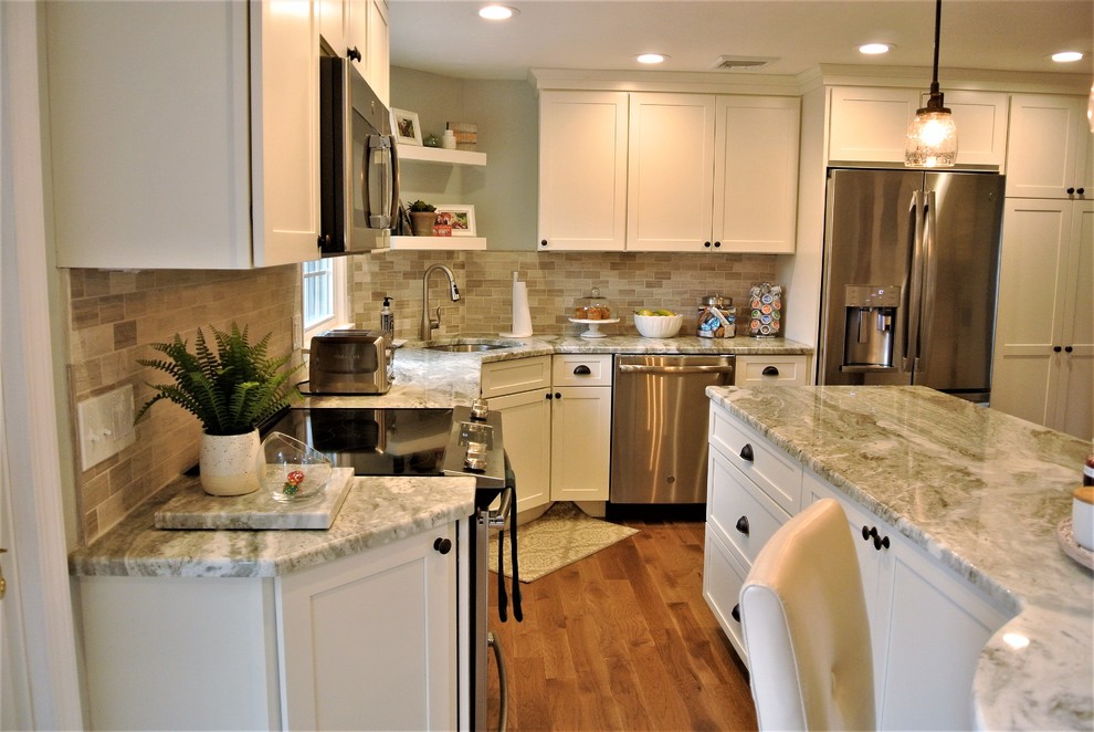 Transitional l-shaped medium tone wood floor kitchen photo in Boston with an undermount sink, shaker cabinets, white cabinets, granite countertops, beige backsplash, subway tile backsplash, stainless steel appliances and an island