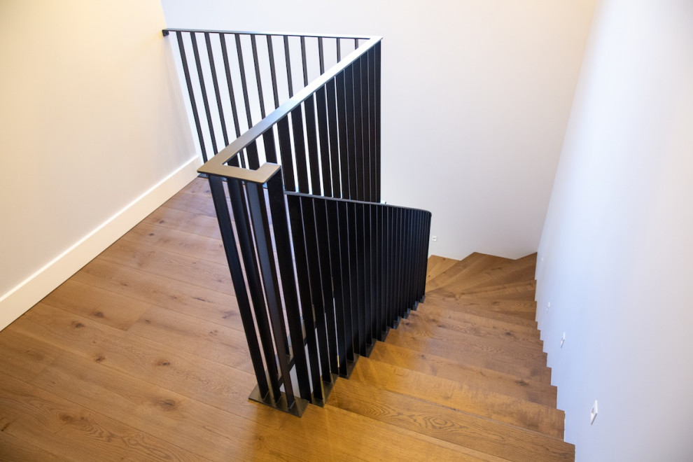 Idéer för en stor modern svängd trappa i trä, med sättsteg i trä och räcke i metall