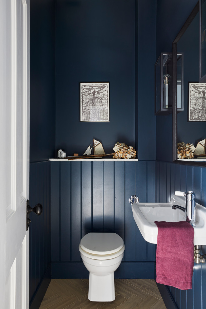 ロンドンにある小さなトランジショナルスタイルのおしゃれなトイレ・洗面所 (壁掛け式トイレ、青い壁、淡色無垢フローリング、壁付け型シンク、大理石の洗面台、フローティング洗面台) の写真