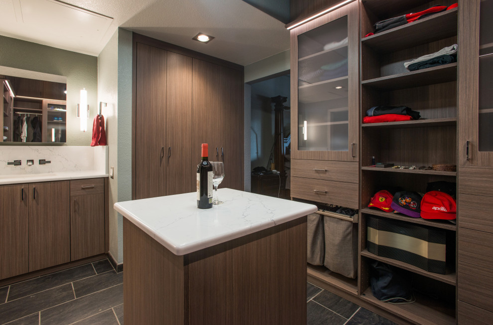 This is an example of a mid-sized modern men's walk-in wardrobe in Denver with flat-panel cabinets, medium wood cabinets, ceramic floors, grey floor and vaulted.