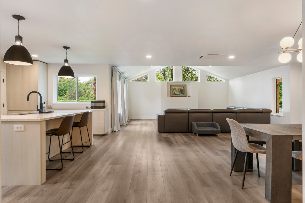 Réalisation d'une salle à manger ouverte sur le salon minimaliste de taille moyenne avec un mur blanc, un sol en vinyl et un sol marron.