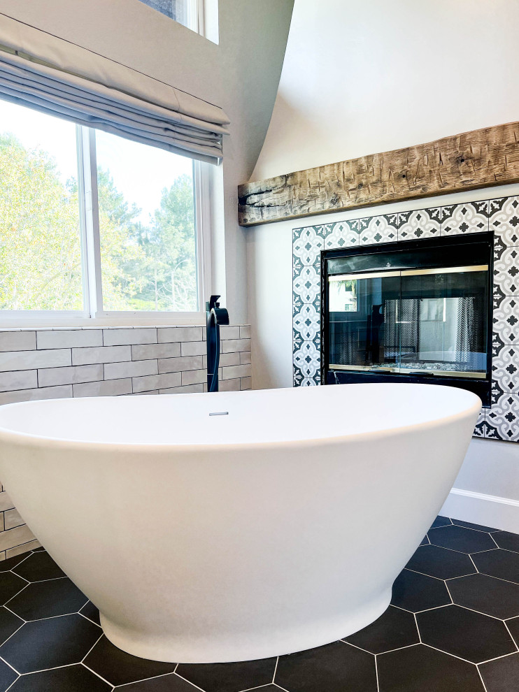 Mediterranean bathroom in Orange County with a freestanding tub, porcelain floors and black floor.