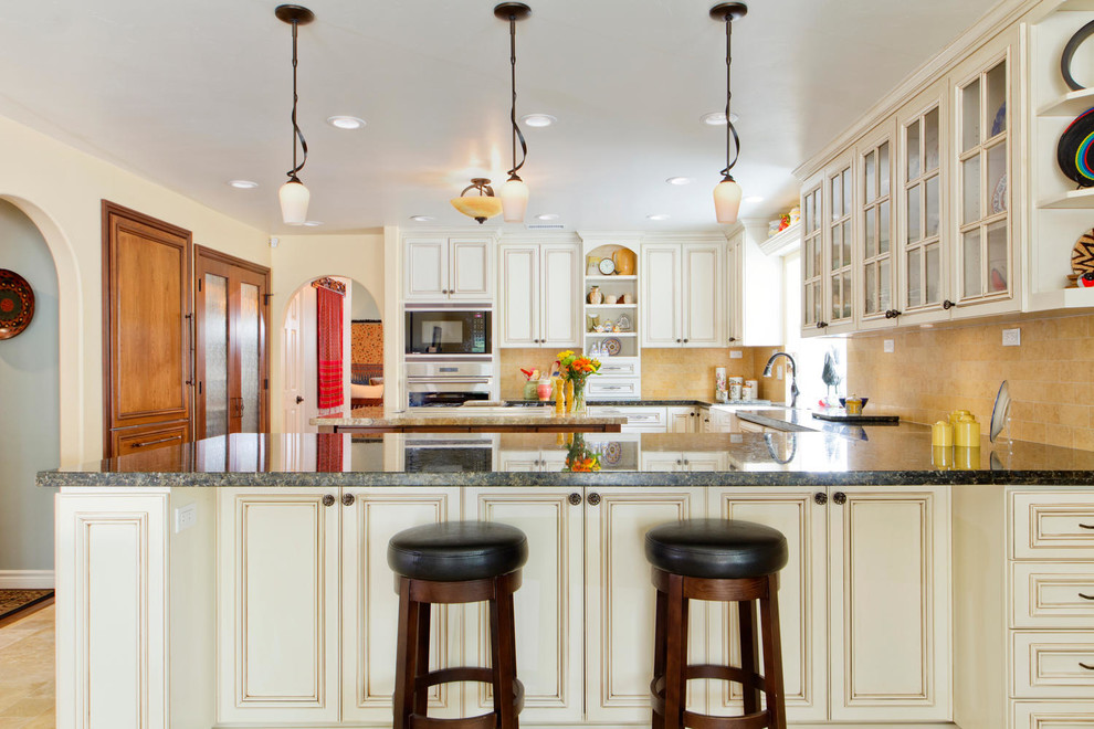 This is an example of a country u-shaped kitchen in San Diego with a farmhouse sink, recessed-panel cabinets, white cabinets, yellow splashback and with island.