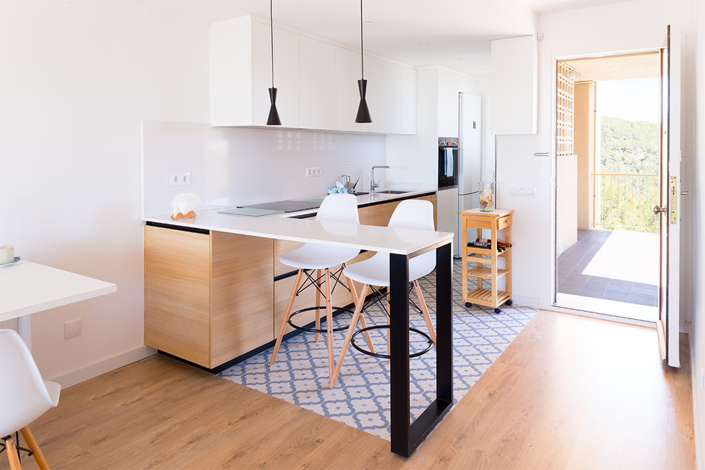 This is an example of a small mediterranean l-shaped open plan kitchen in Other with flat-panel cabinets, light wood cabinets, quartz benchtops, white splashback, with island, blue floor and white benchtop.