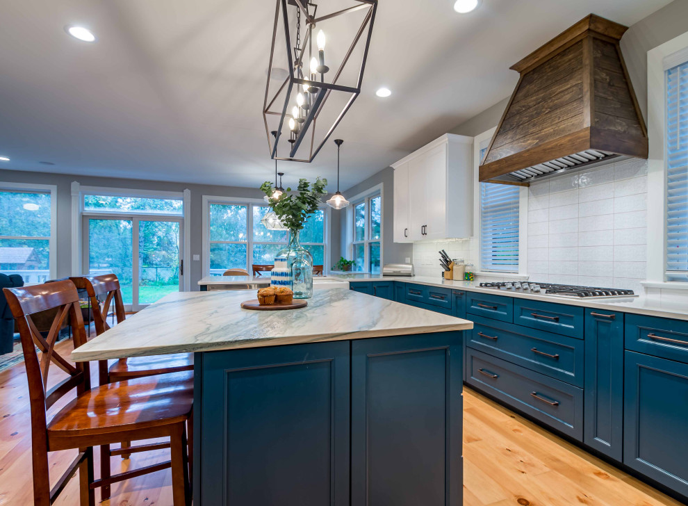 Large country l-shaped eat-in kitchen in Chicago with shaker cabinets, turquoise cabinets, marble benchtops, white splashback, porcelain splashback, stainless steel appliances, with island, multi-coloured benchtop, a farmhouse sink, light hardwood floors, brown floor and wallpaper.