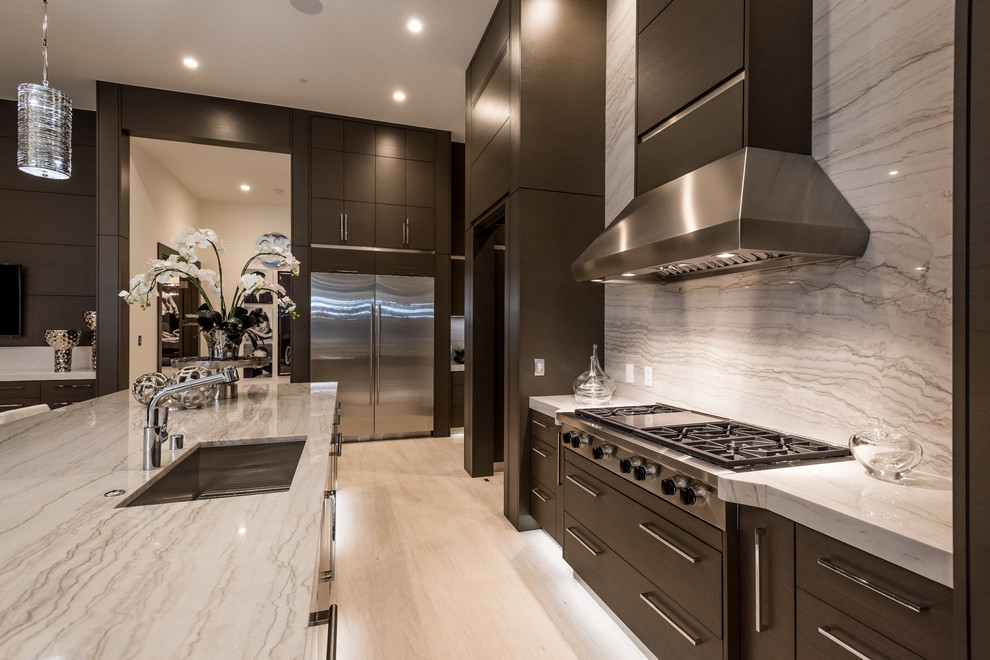 Photo of a mid-sized contemporary l-shaped open plan kitchen in Las Vegas with an undermount sink, dark wood cabinets, granite benchtops, stainless steel appliances, travertine floors, with island, flat-panel cabinets, white splashback, stone slab splashback and grey floor.