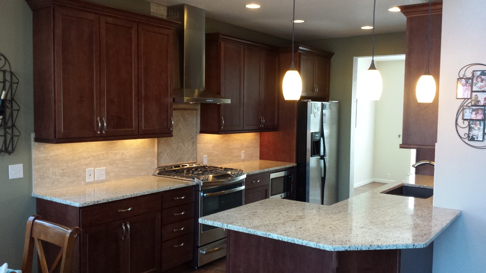 Kitchen - kitchen idea in Denver with recessed-panel cabinets, dark wood cabinets, stainless steel appliances and a peninsula