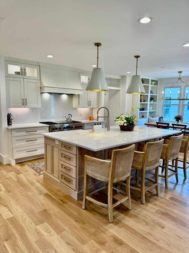 Mid-sized transitional l-shaped light wood floor, brown floor and wallpaper ceiling eat-in kitchen photo in Atlanta with a farmhouse sink, shaker cabinets, white cabinets, granite countertops, white backsplash, stainless steel appliances, an island and white countertops
