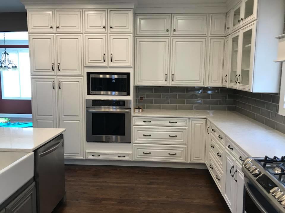 Example of a mid-sized transitional u-shaped medium tone wood floor and brown floor open concept kitchen design in Cincinnati with a farmhouse sink, glass-front cabinets, white cabinets, quartz countertops, gray backsplash, subway tile backsplash, stainless steel appliances, an island and white countertops