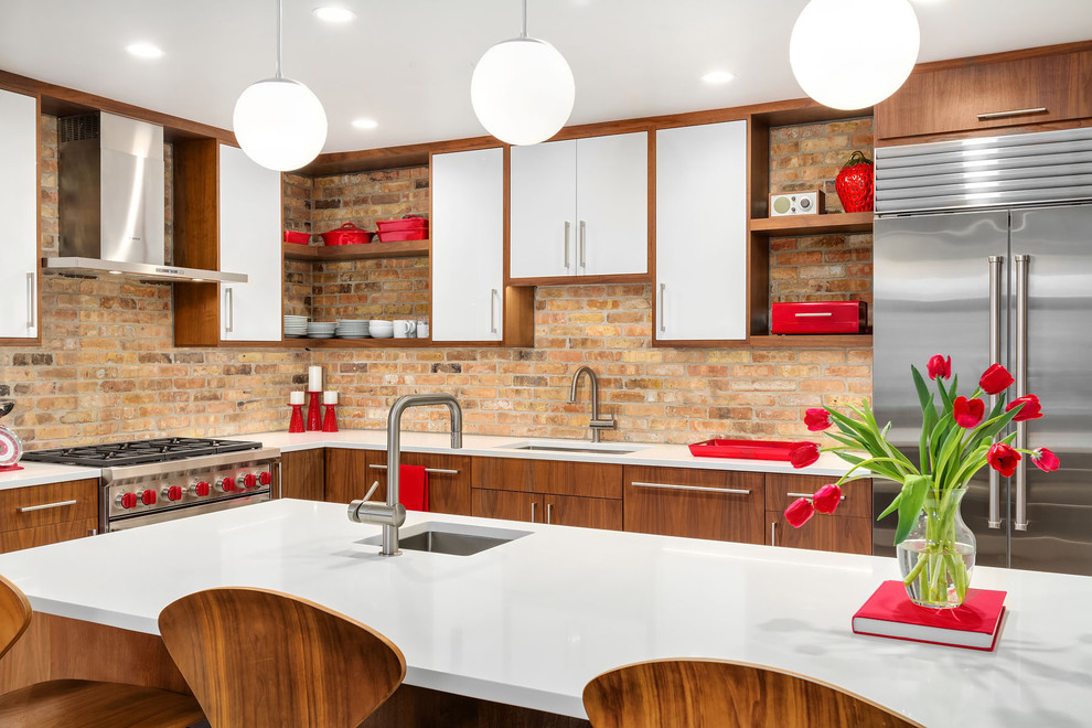 Photo of a midcentury l-shaped kitchen in Chicago with an undermount sink, flat-panel cabinets, dark wood cabinets, brown splashback, brick splashback, stainless steel appliances, with island, white benchtop and quartz benchtops.
