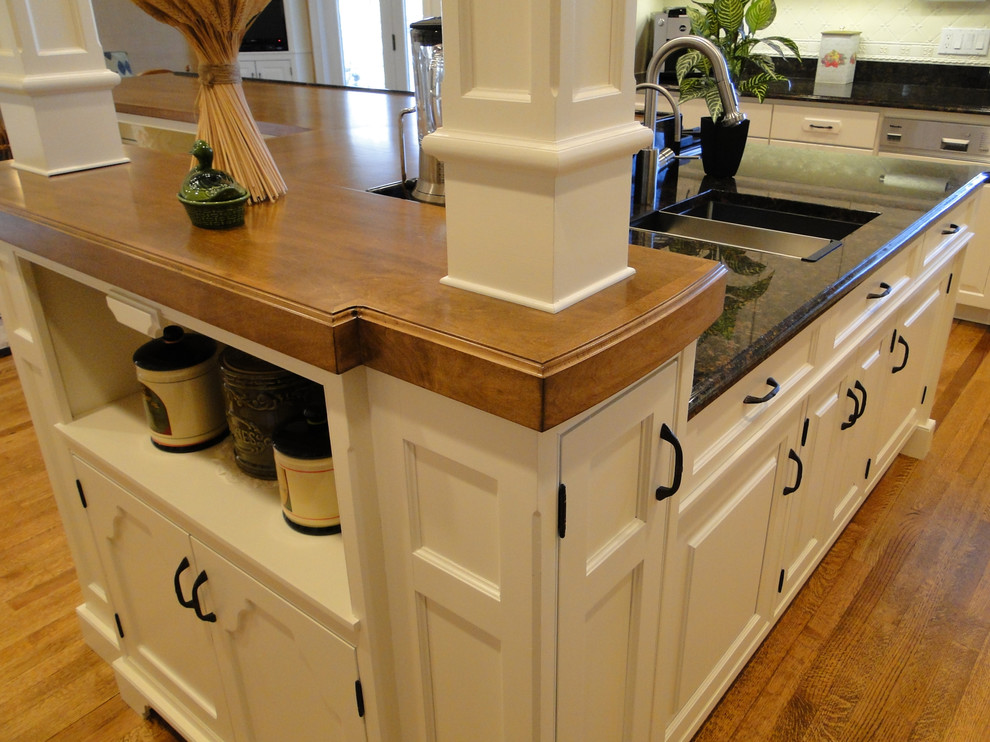 Enclosed kitchen - mid-sized transitional medium tone wood floor and brown floor enclosed kitchen idea in Boston with an undermount sink, raised-panel cabinets, white cabinets, granite countertops, white backsplash, porcelain backsplash, an island and black countertops