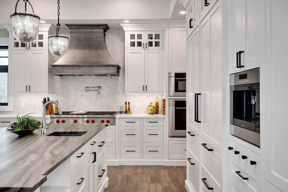 Kitchen - huge transitional u-shaped dark wood floor and brown floor kitchen idea in Calgary with shaker cabinets, white cabinets, marble countertops, marble backsplash, stainless steel appliances, an island, white countertops and white backsplash