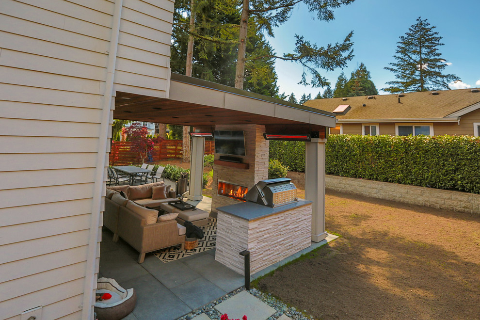 Photo of a mid-sized modern backyard patio in Seattle with an outdoor kitchen, concrete pavers and a roof extension.