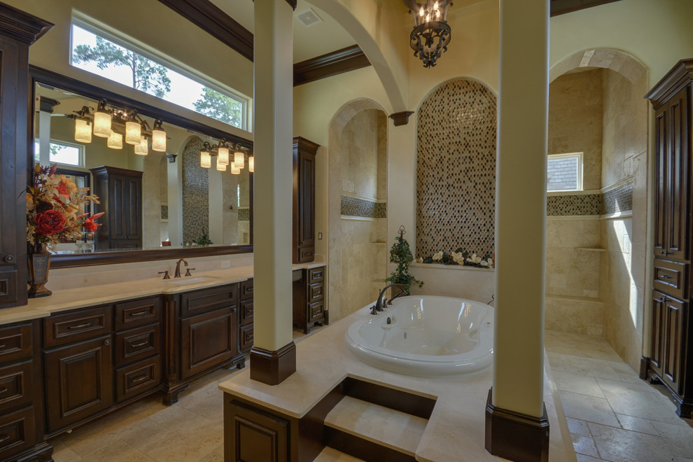 Inspiration for a large mediterranean master bathroom in Houston with yellow walls, marble floors, an undermount sink, beige floor, an open shower, raised-panel cabinets, dark wood cabinets, a drop-in tub, an open shower, beige tile, brown tile, multi-coloured tile, mosaic tile and solid surface benchtops.