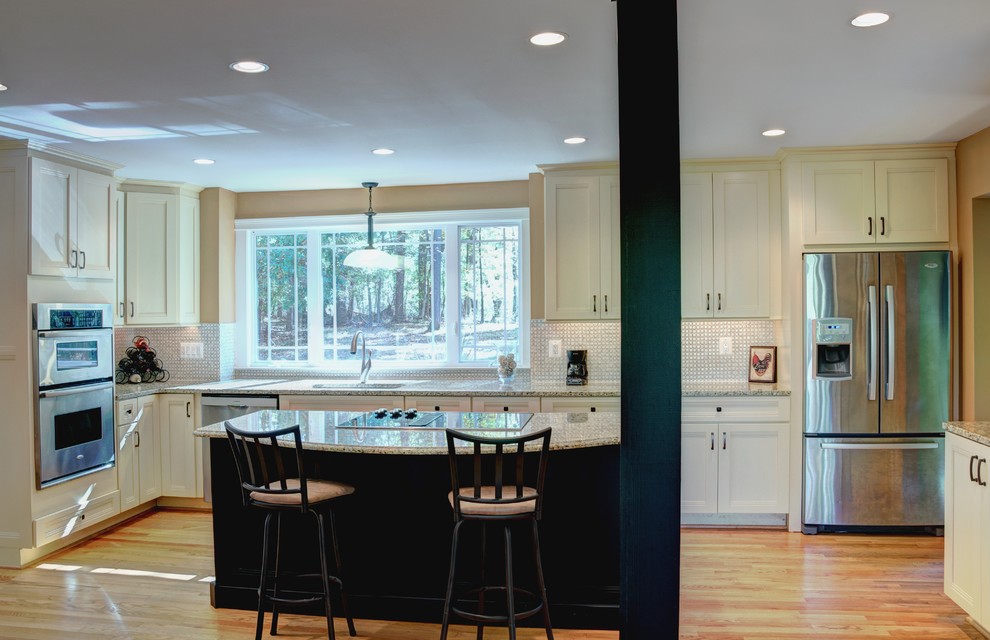 Inspiration for a large transitional single-wall medium tone wood floor eat-in kitchen remodel in Baltimore with an undermount sink, recessed-panel cabinets, yellow cabinets, granite countertops, beige backsplash, ceramic backsplash, stainless steel appliances and an island
