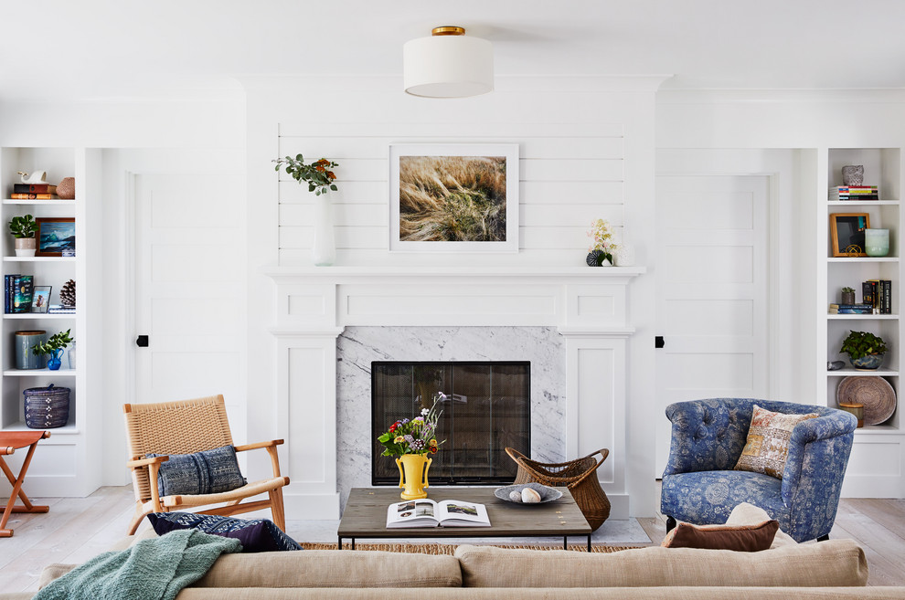 This is an example of a beach style formal living room in Providence with white walls, light hardwood floors, a standard fireplace, a stone fireplace surround and no tv.