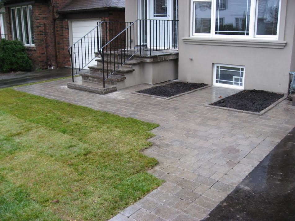 This is an example of a mid-sized traditional front yard full sun driveway for spring in Toronto with a container garden and concrete pavers.