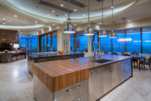 Open concept kitchen with stainless steel cabinets, wood countertops and warm pendant lighting