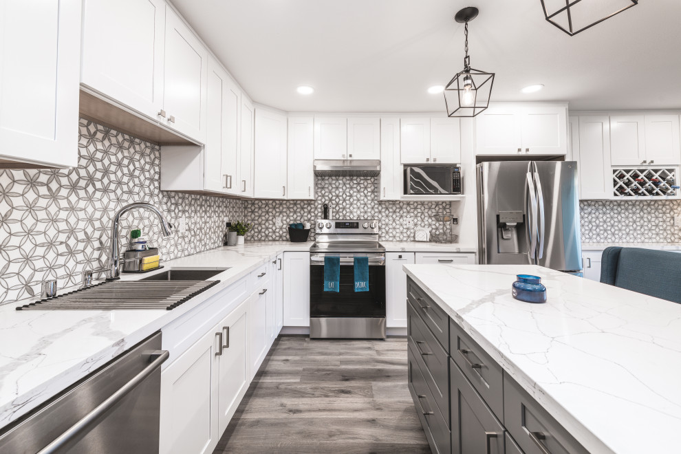 Photo of a large modern l-shaped eat-in kitchen in San Francisco with an undermount sink, shaker cabinets, white cabinets, quartz benchtops, grey splashback, mosaic tile splashback, stainless steel appliances, vinyl floors, with island, grey floor and white benchtop.