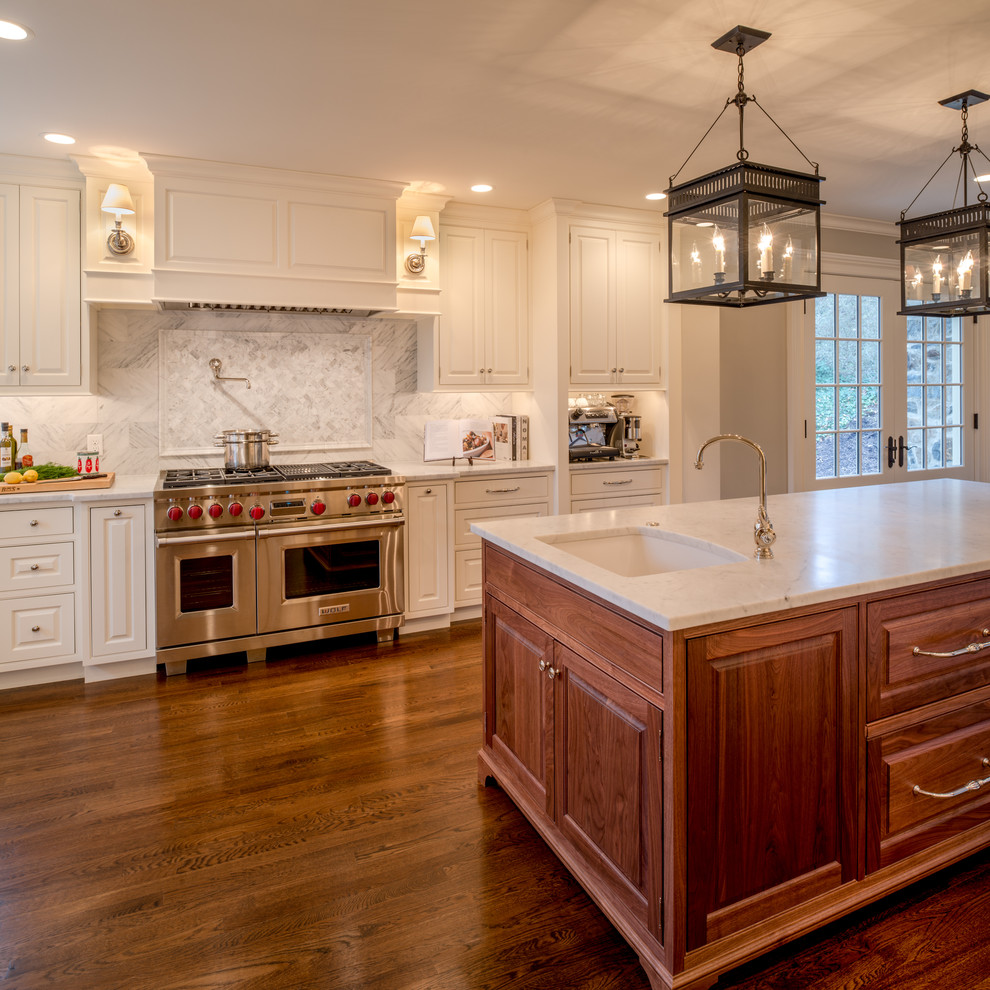 Inspiration for a large traditional u-shaped open plan kitchen in Philadelphia with a farmhouse sink, raised-panel cabinets, marble benchtops, panelled appliances, with island, white cabinets, grey splashback and dark hardwood floors.