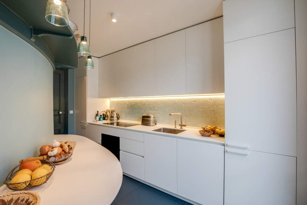 Photo of a small contemporary galley kitchen in Paris with an undermount sink, white cabinets, mosaic tile splashback, panelled appliances, ceramic floors, no island, white benchtop, flat-panel cabinets, grey splashback and blue floor.