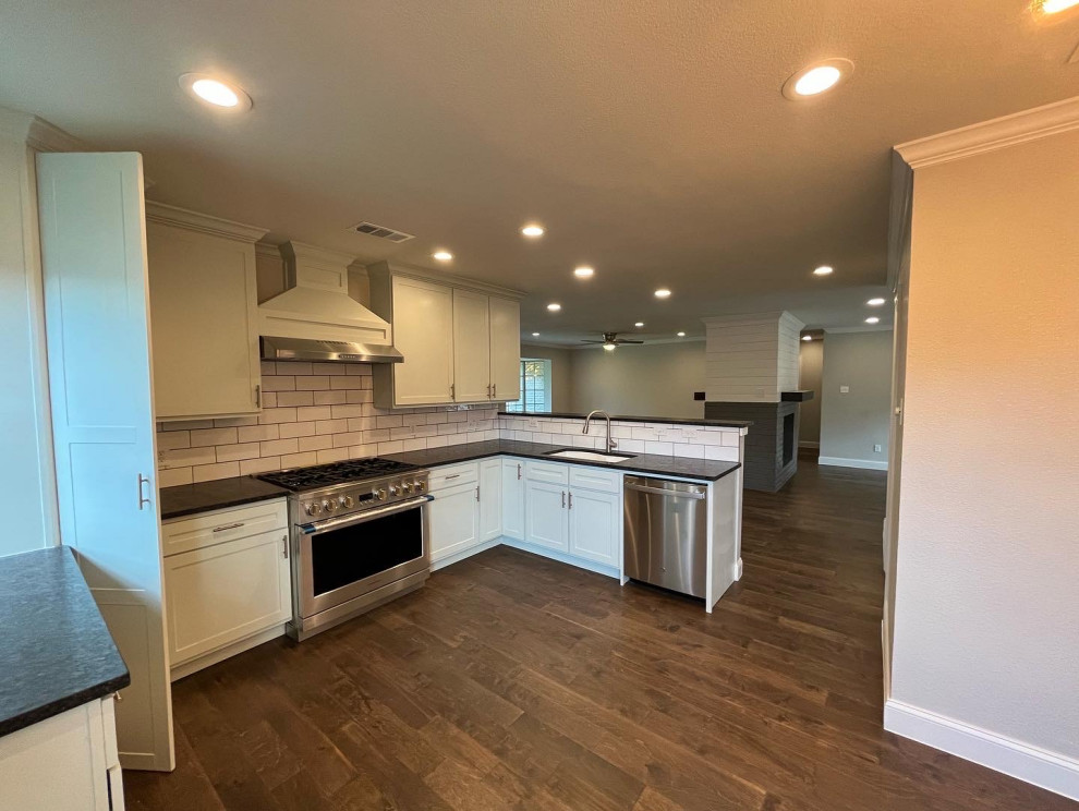 Example of a mid-sized transitional u-shaped dark wood floor and brown floor open concept kitchen design in Dallas with an undermount sink, shaker cabinets, green cabinets, quartz countertops, white backsplash, subway tile backsplash, stainless steel appliances, a peninsula and black countertops