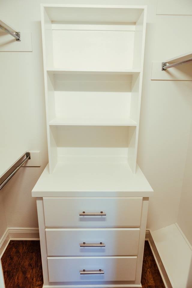 Photo of a mid-sized transitional gender-neutral walk-in wardrobe in New Orleans with open cabinets, white cabinets, dark hardwood floors and brown floor.