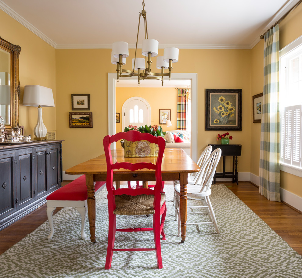 Eclectic dining room in Little Rock with yellow walls, medium hardwood floors and brown floor.