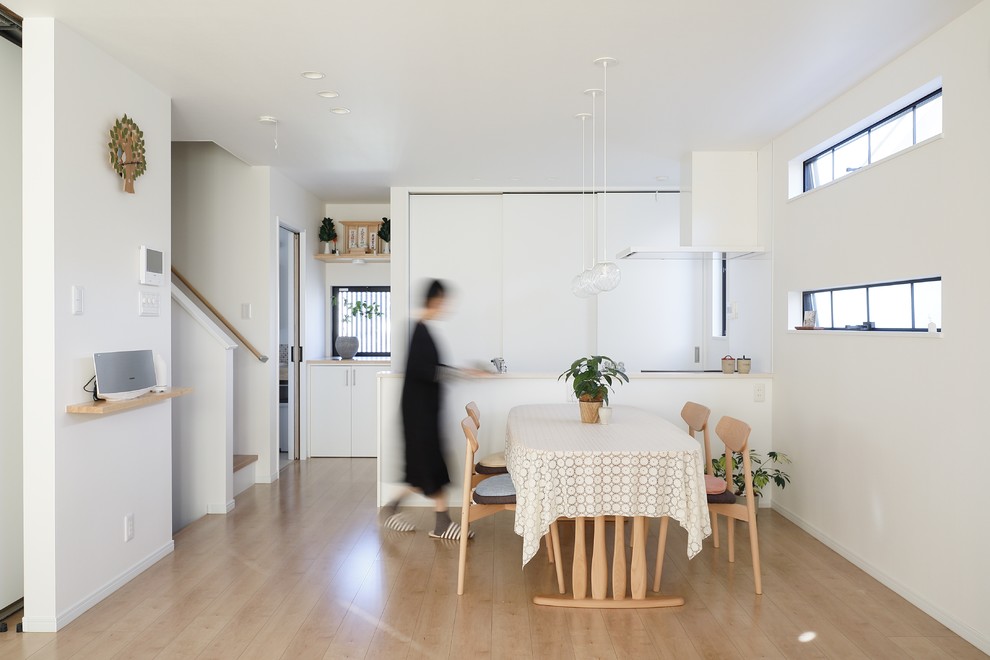 Modern open plan dining in Kyoto with white walls, light hardwood floors and beige floor.