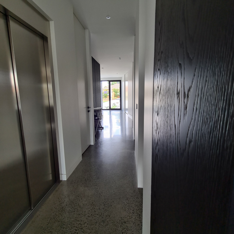 На фото: большой коридор в современном стиле с белыми стенами, бетонным полом и серым полом с