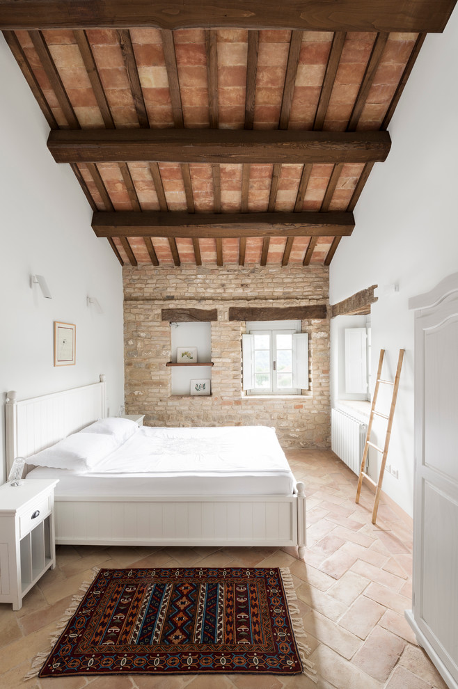 Mid-sized country master bedroom in Tel Aviv with white walls and terra-cotta floors.
