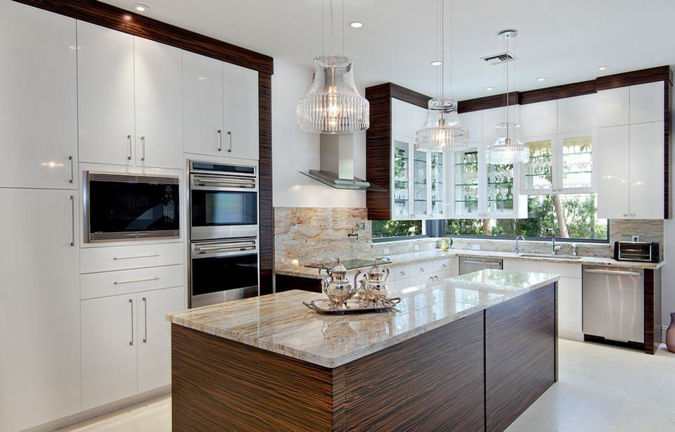 Mid-sized contemporary l-shaped open plan kitchen in Miami with an undermount sink, flat-panel cabinets, white cabinets, quartzite benchtops, beige splashback, stone slab splashback, stainless steel appliances, travertine floors, with island and beige floor.