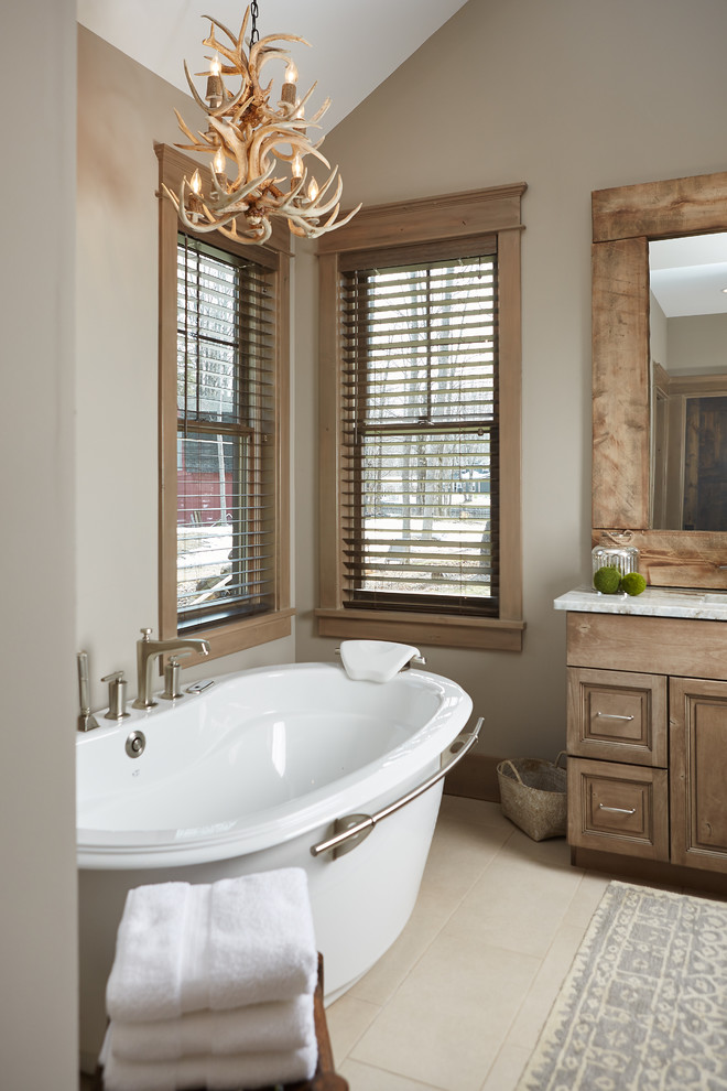Photo of a country master bathroom in Grand Rapids with an undermount sink, flat-panel cabinets, medium wood cabinets, granite benchtops, a freestanding tub, an alcove shower, beige tile, porcelain tile, beige walls and ceramic floors.
