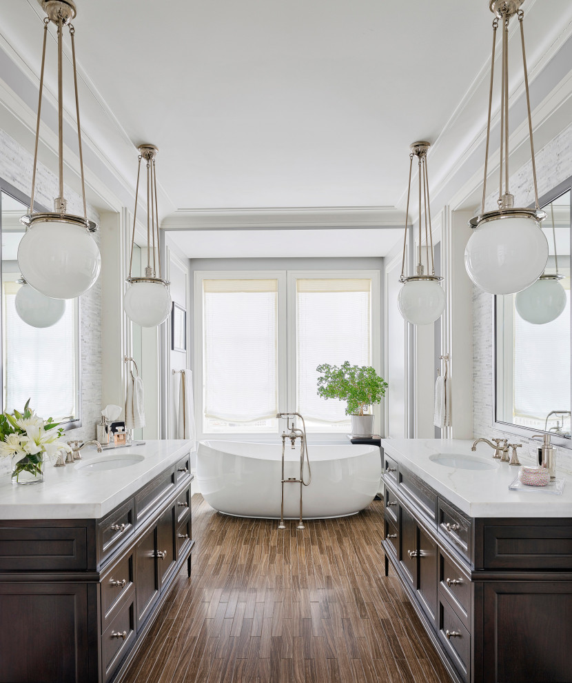 Inspiration for a transitional bathroom in Chicago with shaker cabinets, dark wood cabinets, a freestanding tub, white tile, medium hardwood floors, an undermount sink, brown floor and white benchtops.