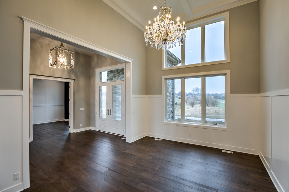 This is an example of a large country formal enclosed living room in Omaha with dark hardwood floors, beige walls, no fireplace and brown floor.