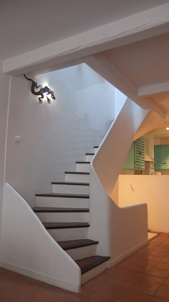Idée de décoration pour un grand escalier carrelé courbe méditerranéen avec des contremarches carrelées.