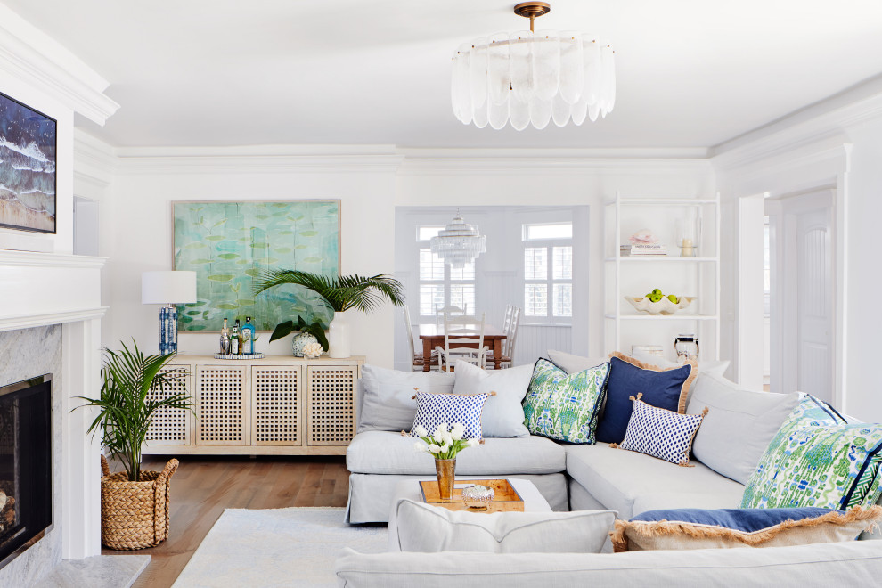 Inspiration for a large beach style open concept living room in New York with white walls, a standard fireplace, a stone fireplace surround, brown floor, medium hardwood floors, a wall-mounted tv and decorative wall panelling.